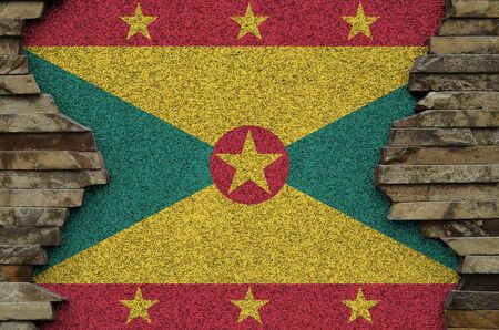 Grenada flag depicted in paint colors on old stone wall close up. Textured banner on rock wall backgroundの写真素材