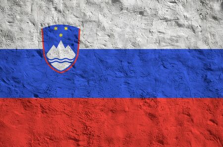 Slovenia flag depicted in bright paint colors on old relief plastering wall close up. Textured banner on rough backgroundの写真素材