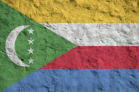 Comoros flag depicted in bright paint colors on old relief plastering wall close up. Textured banner on rough backgroundの写真素材