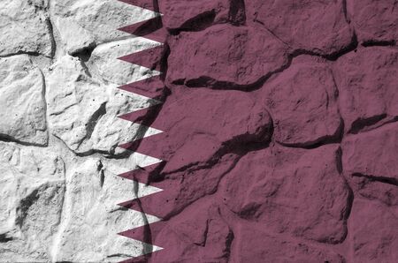 Qatar flag depicted in paint colors on old stone wall close up. Textured banner on rock wall...
