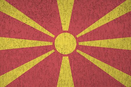 Macedonia flag depicted in bright paint colors on old relief plastering wall close up. Textured banner on rough backgroundの写真素材