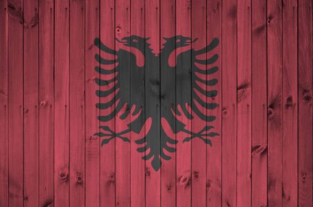 Albania flag depicted in bright paint colors on old wooden wall close up. Textured banner on rough backgroundの写真素材