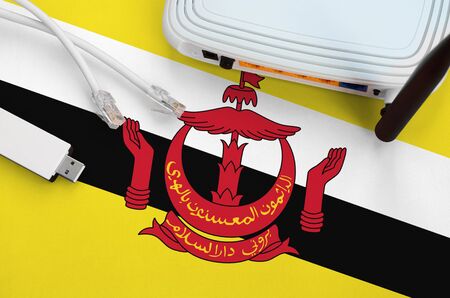 Brunei Darussalam flag depicted on table with internet rj45 cable, wireless usb wifi adapter and...