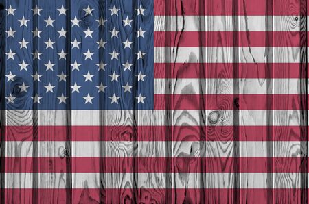United States of America flag depicted in bright paint colors on old wooden wall close up. Textured...
