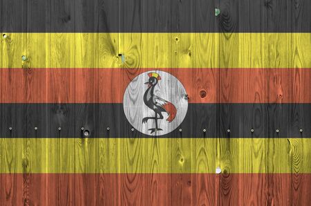 Uganda flag depicted in bright paint colors on old wooden wall close up. Textured banner on rough backgroundの写真素材