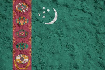 Turkmenistan flag depicted in bright paint colors on old relief plastering wall close up. Textured banner on rough backgroundの写真素材