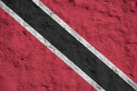 Trinidad and Tobago flag depicted in bright paint colors on old relief plastering wall close up. Textured banner on rough backgroundの写真素材