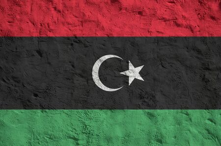 Libya flag depicted in bright paint colors on old relief plastering wall close up. Textured banner on rough backgroundの写真素材