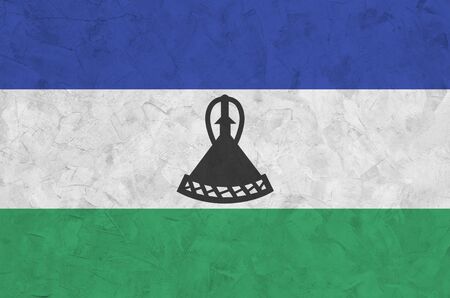 Lesotho flag depicted in bright paint colors on old relief plastering wall close up. Textured banner on rough backgroundの写真素材