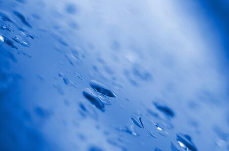 Small water rain drops on blue glass in macro. Abstract nature background, phantom classic blue colorの写真素材