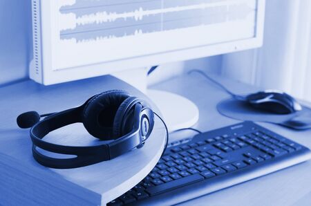 Big black headphones lie on the wooden desktop of the sound designer. Workplace for music creator. Selective focus. phantom classic blue color toneの写真素材