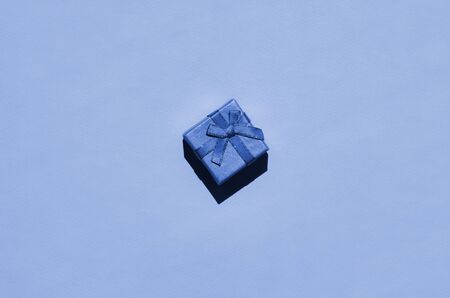 Small gift box lie on texture background of fashion trendy phantom classic blue color paper in...