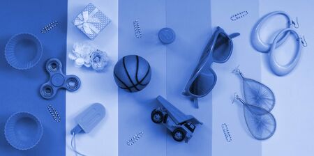 Trendy pastel composition with earrings, sunglasses, beverage can, basketball ball, toy truck, gift box, ice cream, flower and spinner. phantom classic blue color.の写真素材