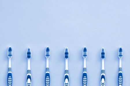 A lot of toothbrushes lie on a phantom classic blue color background. Top view, flat lay. Minimal...