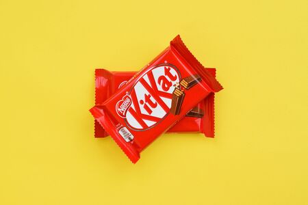 NY, USA - DECEMBER 4, 2019: Kit Kat chocolate bar in red wrapping lies on yellow background. Kit kat created by Rowntree's of York in United Kingdom and is now produced globally by Nestleのeditorial素材