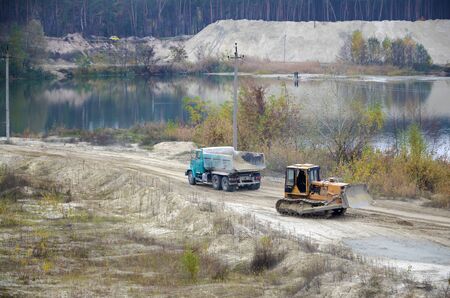 Caterpillar loader and dump truck works at the opencast mining quarry. Heavy machinery in the open...