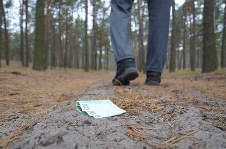 Young boy loses his euro money bills on Russian autumn fir wood path. Carelessness and losing money...