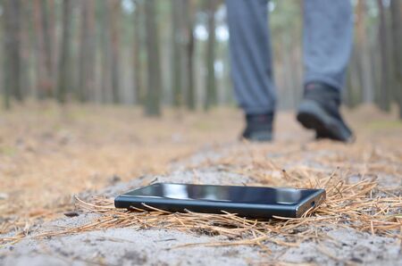 Young boy loses his smartphone on Russian autumn fir wood path. Carelessness and losing expensive...