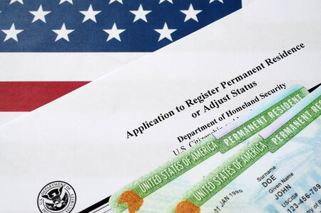 I-485 Application to register permanent residence or adjust status form and green card from dv-lottery lies on United States flag from Department of Homeland Security close upの写真素材