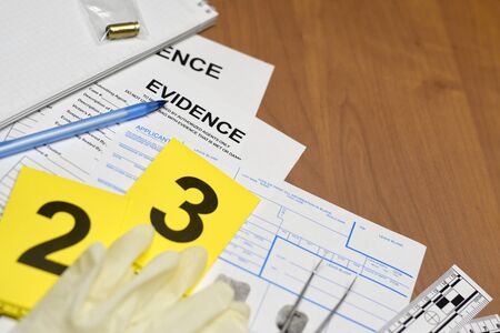 Paperwork during crime scene investigation process in csi laboratory. Evidence labels with fingerprint applicant and rubber gloves on vooden table close upの写真素材