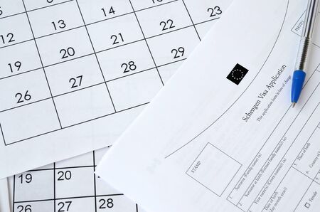 Schengen Visa application form and blue pen on paper calendar page close up