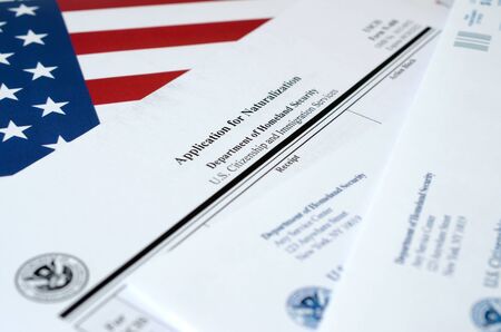 N-400 Application for Naturalization blank form lies on United States flag with envelope from Department of Homeland Security close upの写真素材