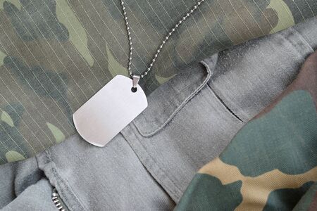 Silvery military beads with dog tag on different camouflage fatigue uniforms. Army token on soldiers camo jacketsの写真素材