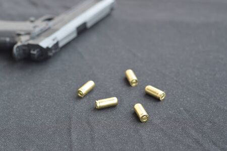9mm bullets and pistol lie on a black fabric. A set shooting range items or a self-defense kit....