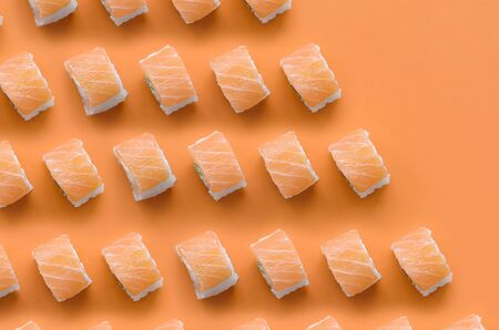 Philadelphia rolls with salmon on orange background close up. Minimalism top view flat lay pattern with Japanese foodの写真素材