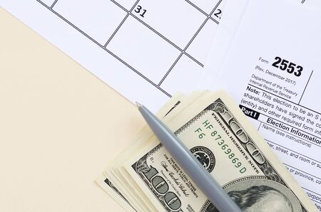 IRS Form 2553 Election by a Small Business Corporation tax blank lies with pen and many hundred dollar bills on calendar page. Tax period concept. Copy space for textの写真素材