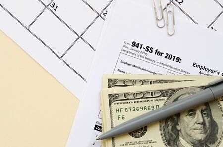 IRS Form 941-SS Employer's quarterly federal tax return blank lies with pen and many hundred dollar...