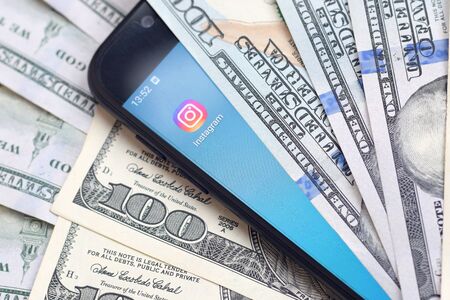 KHARKOV, UKRAINE - FEBRUARY 6, 2020: Smartphone screen with Instagram app and lot of hundred dollar bills. Business and social networking conceptのeditorial素材