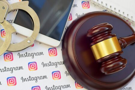 KHARKOV, UKRAINE - FEBRUARY 17, 2020: Instagram paper logo lies with wooden judge gavel, smartphone...