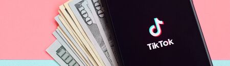 KHARKOV, UKRAINE - FEBRUARY 16, 2020: Tiktok application on samsung smartphone screen and dollar bills. TikTok is a popular video-sharing social networking service owned by ByteDanceのeditorial素材