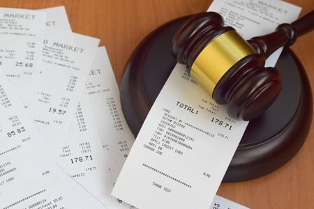 Justice mallet and many supermarket receipts on wooden table close upの写真素材