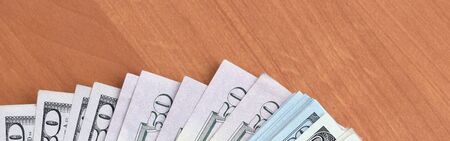 Fan of many one hundred and fifty dollar bills on wooden background surface close up. Flat lay top...