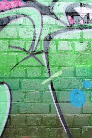 Abstract colorful fragment of graffiti paintings on old brick wall in green colors. Street art composition with parts of unwritten letters and multicolored stains. Subcultural background textureの写真素材