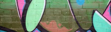 Abstract colorful fragment of graffiti paintings on old brick wall in green colors. Street art composition with parts of unwritten letters and multicolored stains. Subcultural background textureの写真素材