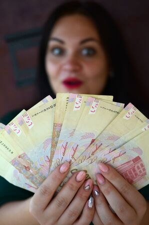 Brunette caucasian girl portrait with big amount of ukrainian money. Hundred hryvnia bills fan