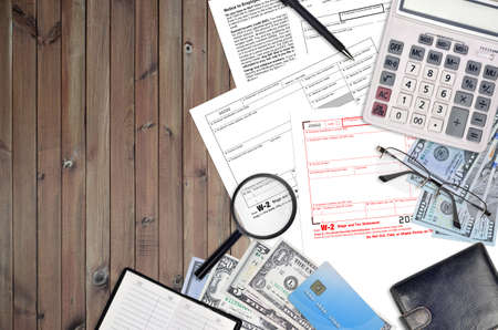 IRS form W-2 wage and tax statement lies on flat lay office table and ready to fill. U.S. Internal revenue services paperwork concept. Time to pay taxes in United States. Top viewの写真素材