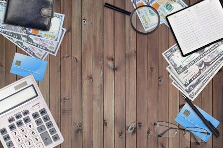 Office flat lay composition with calculator, address book and other office items on brown wooden table background with top view. Accountant paperwork conceptの写真素材