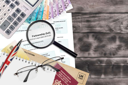 English Tax form sa104 Partnership from HM revenue and customs lies on table with office items. HMRC...