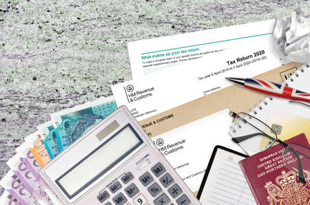 English form sa100 Tax return by HM revenue and customs lies on table with office items. HMRC paperwork and tax paying process in United Kingdom of Great Britainの写真素材