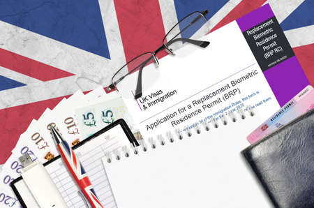 English form BRP RC Application for a replacement biometric residence permit card from UK visas and immigration services lies on table with office items. UK residence permit paperwork processの写真素材