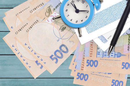 500 Ukrainian hryvnias bills and alarm clock with pen and envelopes. Tax season concept, payment...