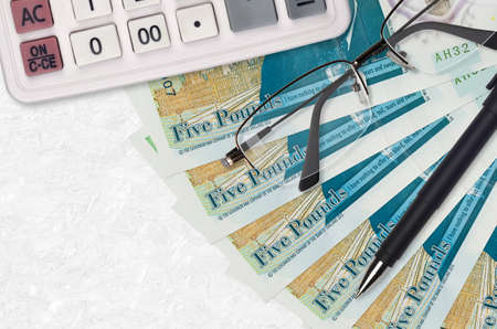 5 British pounds bills fan and calculator with glasses and pen. Business loan or tax payment season...