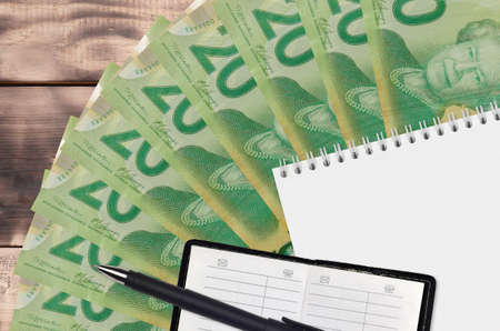 20 Canadian dollars bills fan and notepad with contact book and black pen. Concept of financial planning and business strategy. Accounting and investmentの写真素材