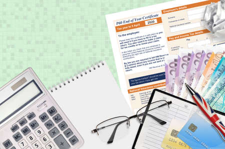 English Tax form P60 End of year certificate by HM revenue and customs lies on table with office...