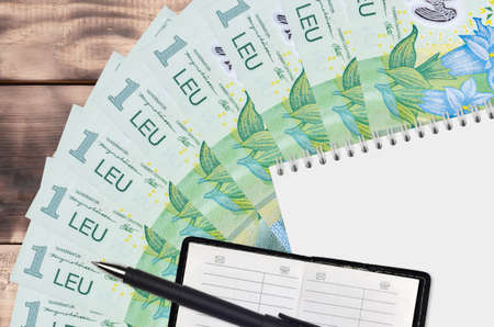 1 Romanian leu bills fan and notepad with contact book and black pen. Concept of financial planning...