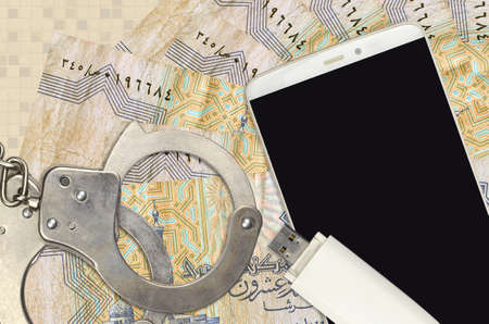25 Egyptian piastres bills and smartphone with police handcuffs. Concept of hackers phishing attacks, illegal scam or online spyware soft distributionの写真素材